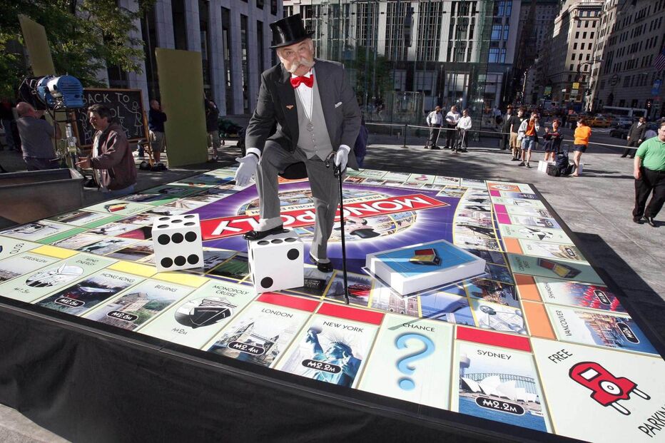 O ‘Sr. Monopólio’ posa em cima de uma versão gigante da mais recente edição do famoso jogo, ‘Monopoly Here Now: The World Edition’, após a sua apresentação no programa matinal do canal norte-americano CBS. (Ray Stubblebine / Reuters).