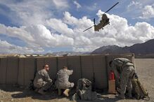 Soldados norte-americanos protegem-se da poeira enquanto um helicóptero Chinook levante voo da base militar de Camp Altamur, no Afeganistão. (Ahmad Masood, Reuters)