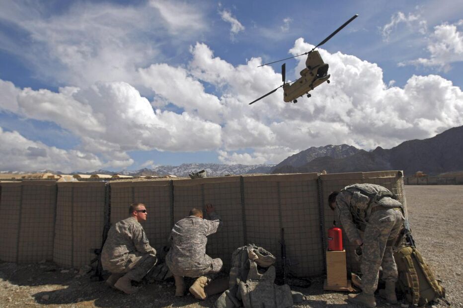 Soldados norte-americanos protegem-se da poeira enquanto um helicóptero Chinook levante voo da base militar de Camp Altamur, no Afeganistão. (Ahmad Masood, Reuters)