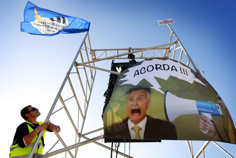 Estivador coloca bandeira num andaime onde está um cartaz com a imagem de Cavaco Silva