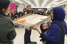 Uma mulher oferece pizza a quem protesta no Aeroporto de Dulles
