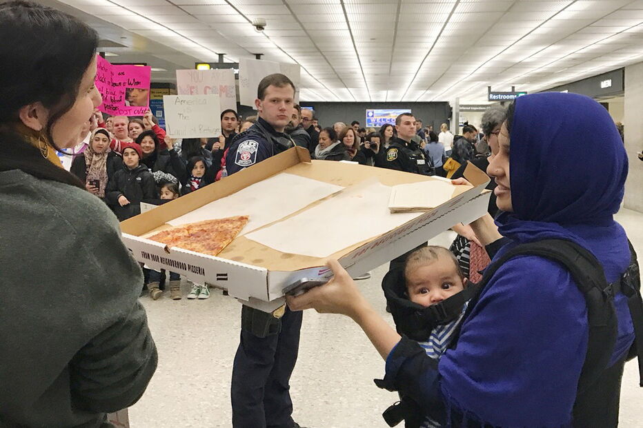 Uma mulher oferece pizza a quem protesta no Aeroporto de Dulles