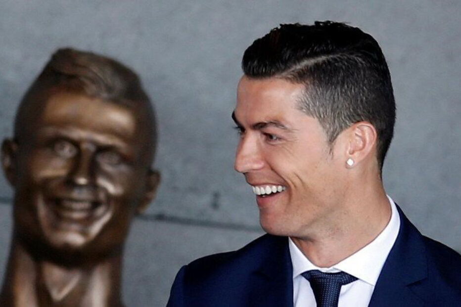 Cristiano Ronaldo junto ao busto que está no aeroporto com o seu nome