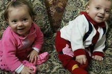 Pai segura nos braços os seus dois filhos mortos