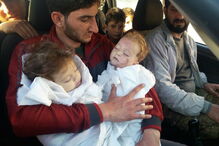 Pai segura nos braços os seus dois filhos mortos