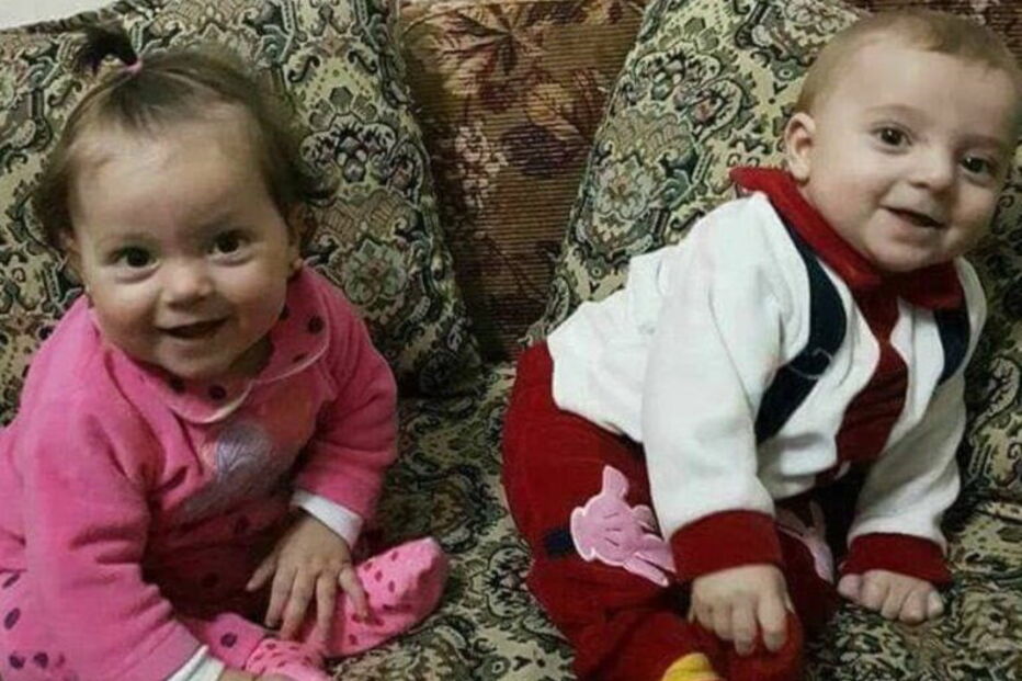 Pai segura nos braços os seus dois filhos mortos