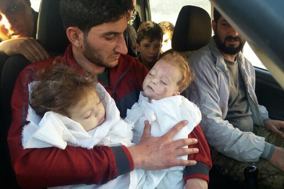 Pai segura nos braços os seus dois filhos mortos