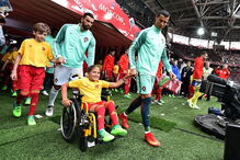 Cristiano Ronaldo entra em campo de mãos dadas com menina em cadeira de rodas