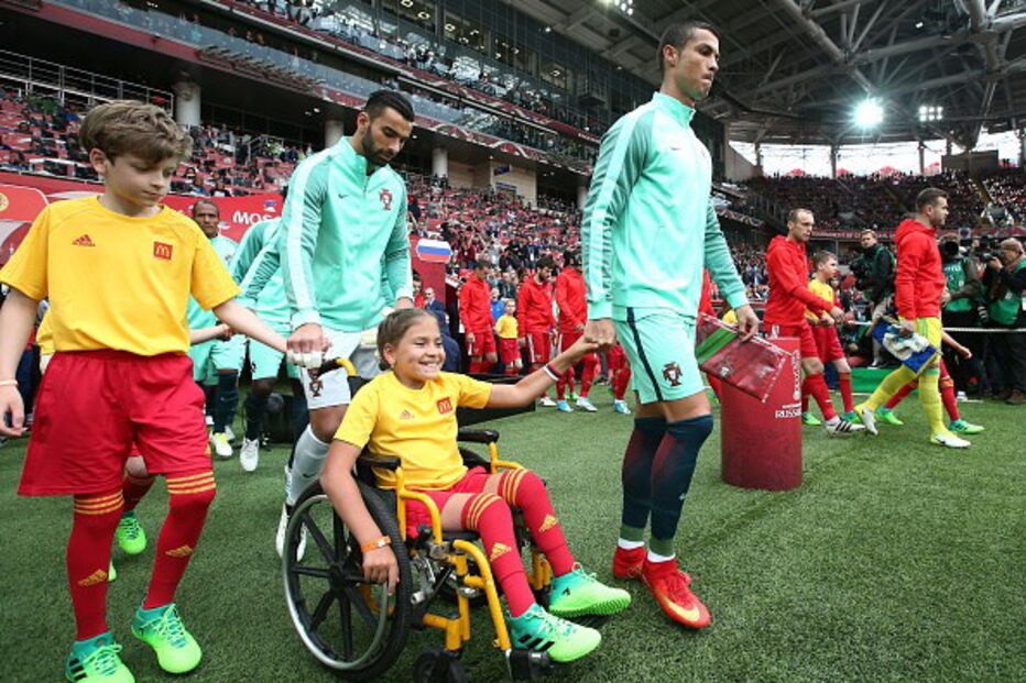 Cristiano Ronaldo entra em campo de mãos dadas com menina em cadeira de rodas