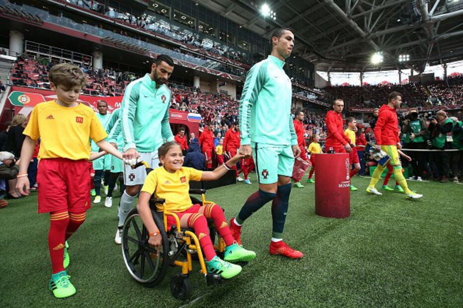 Cristiano Ronaldo entra em campo de mãos dadas com menina em cadeira de rodas