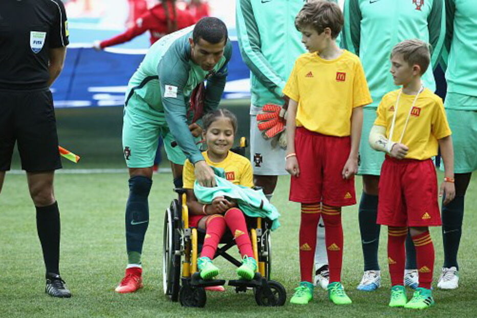 Cristiano Ronaldo entra em campo de mãos dadas com menina em cadeira de rodas
