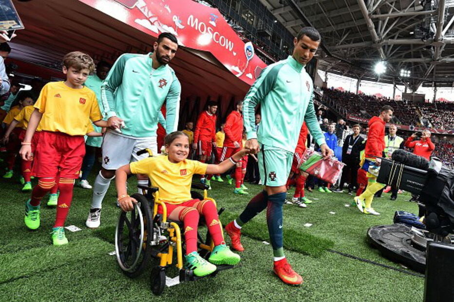 Cristiano Ronaldo entra em campo de mãos dadas com menina em cadeira de rodas