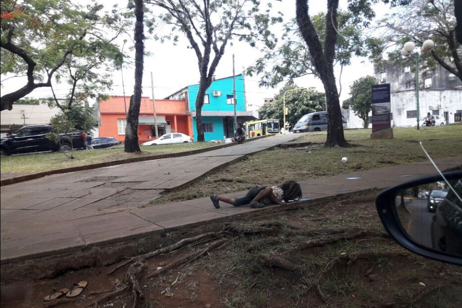 Menina bebe água de um charco na rua