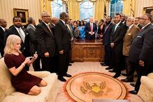 27 de fevereiro - Kellyanne Conway, a conselheira de Donald Trump, ajoelha-se num dos sofás da Sala Oval da Casa Branca enquanto visualiza as fotografias acabadas de tirar ao presidente e aos dirigentes de escolas e universidades americanas negras