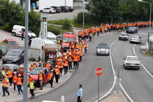 Diversos peregrinos caminham na berma da estrada com coletes refletores em Coimbra