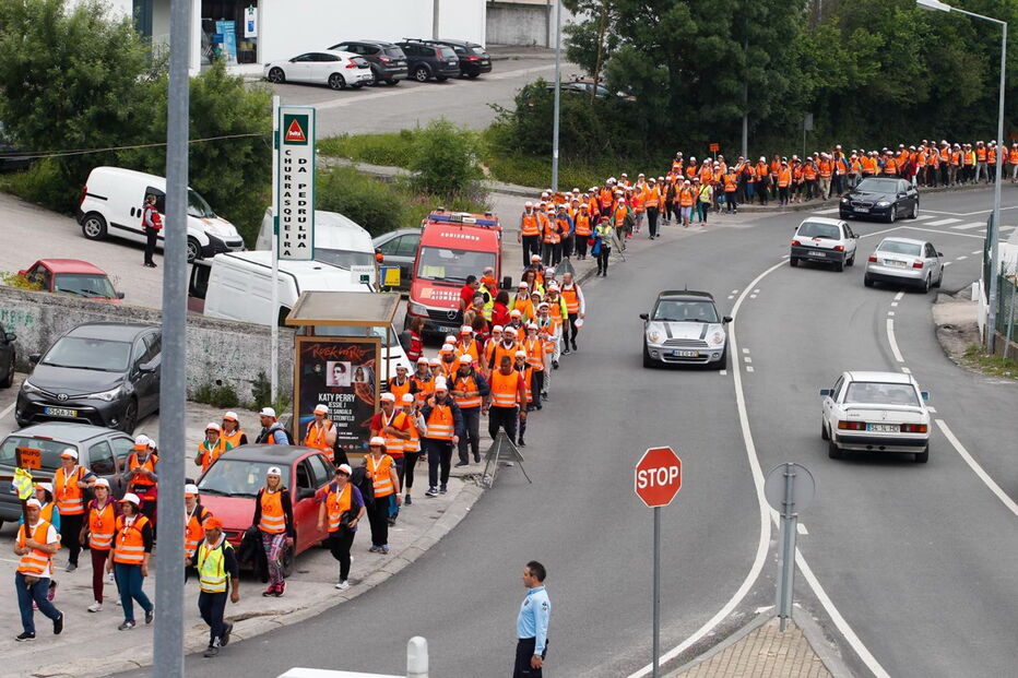 Diversos peregrinos caminham na berma da estrada com coletes refletores em Coimbra