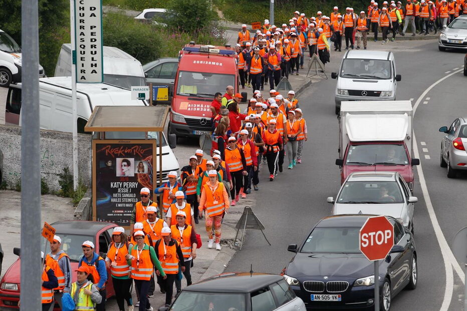 Diversos peregrinos caminham na berma da estrada com coletes refletores em Coimbra