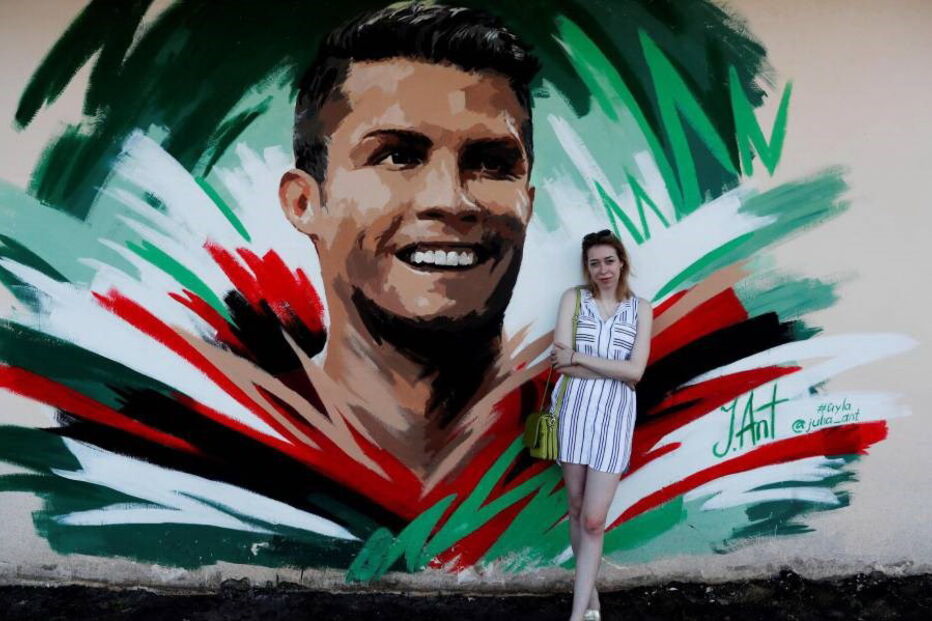 Artista Yulia Antipova ao lado do mural que fez para Ronaldo