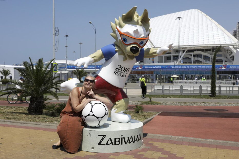 Adeptos aproveitam o calor para estar na praia em frente ao estádio Fisht, em Sochi.