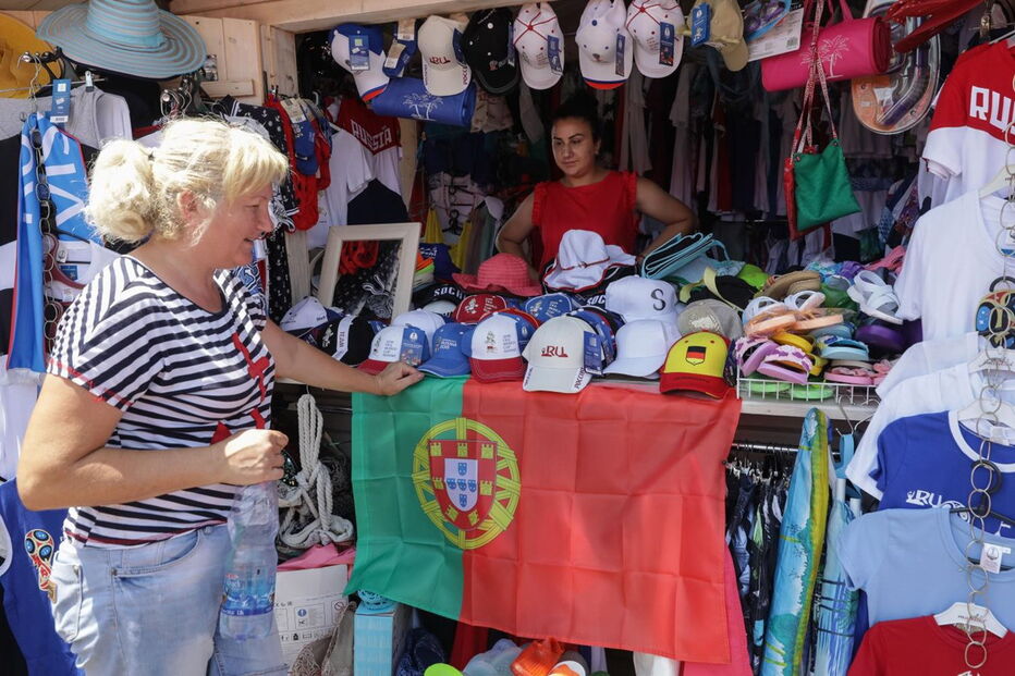 Adeptos aproveitam o calor para estar na praia em frente ao estádio Fisht, em Sochi.