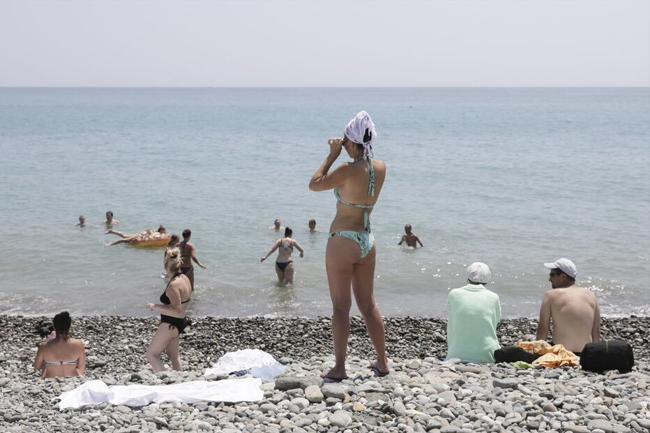 Adeptos aproveitam o calor para estar na praia em frente ao estádio Fisht, em Sochi.