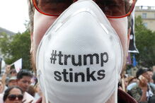 Uma manifestante com uma máscara alusiva a Trump