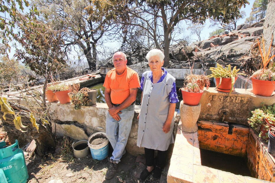 José Eduardo, 60 anos, com a mãe, Maria Margarida, de 83, junto à casa e ao tanque de onde o morador retirou água com baldes para salvar a habitação e animais