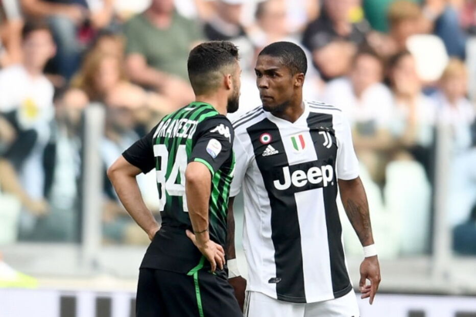 Douglas Costa cospe em adversário durante jogo da Juventus