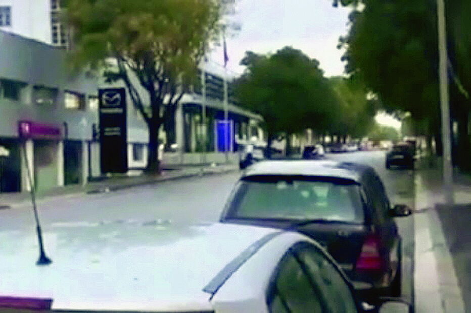 Vídeo amador regista o momento em que um homem, de t-shirt branca e neste frame já em cima do capot,  é atropelado por um carro que inverteu o sentido da marcha antes do embate 