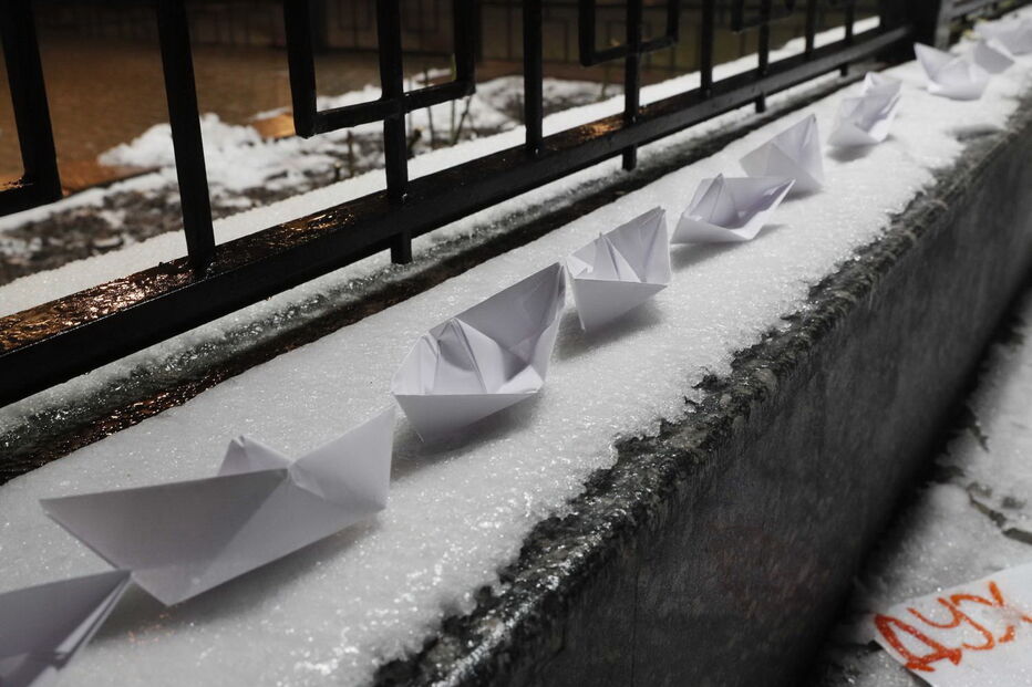Homem coloca vários barcos de papel em frente à embaixada russa em Kiev, na Ucrânia