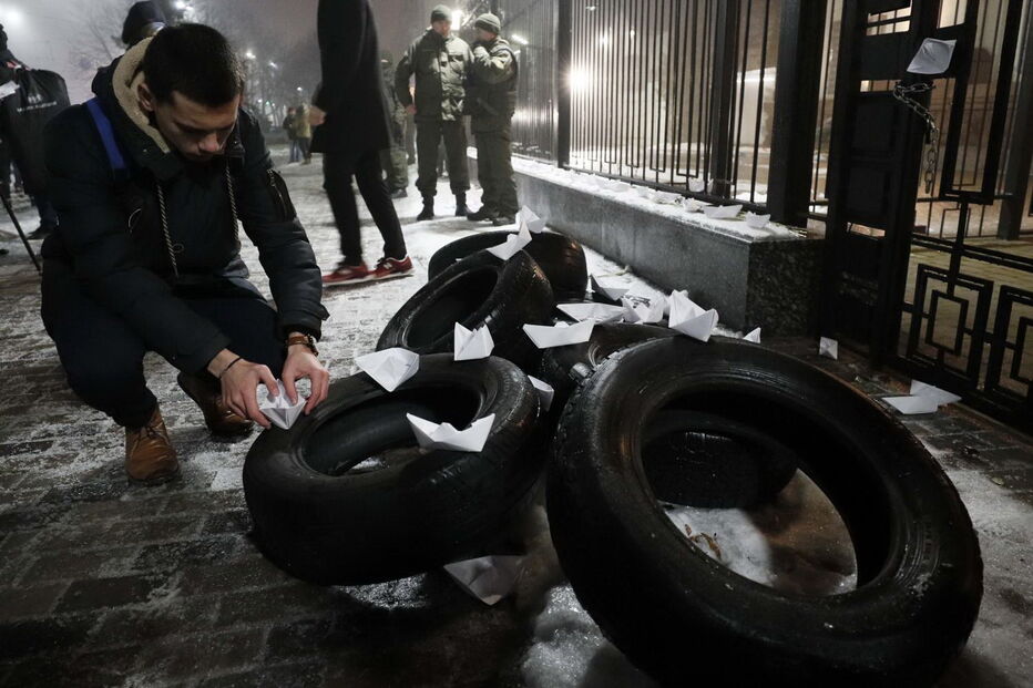Homem coloca vários barcos de papel em frente à embaixada russa em Kiev, na Ucrânia