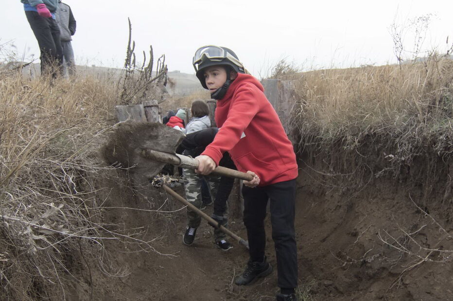 Crianças ucranianas constroem trincheiras, na cidade de Mariupol, para ajudar militares
