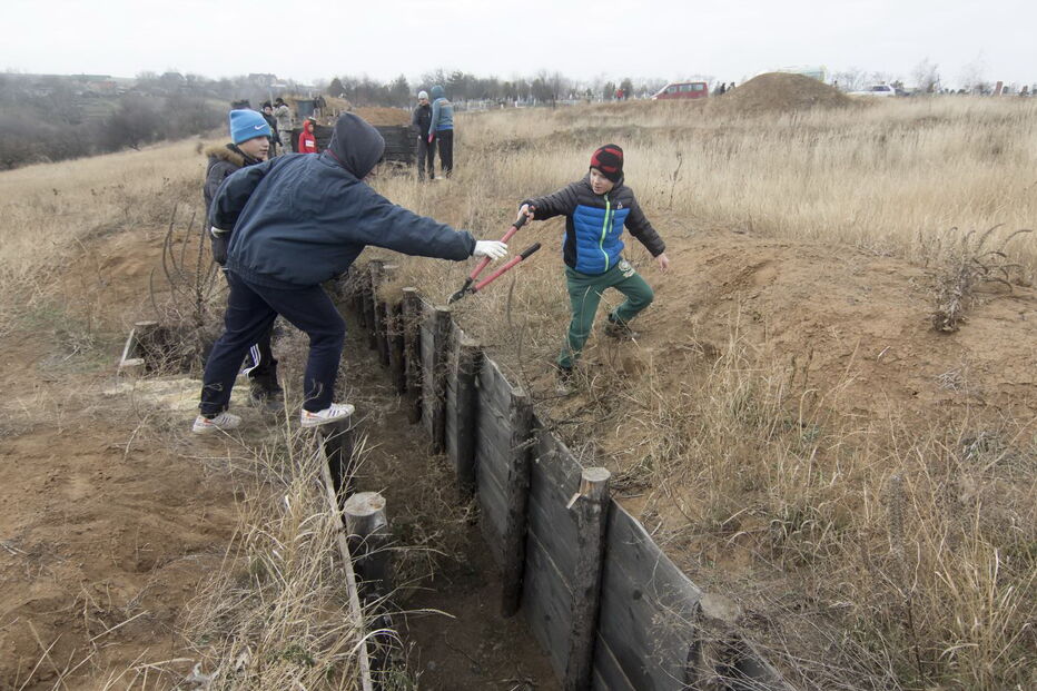 Crianças ucranianas constroem trincheiras, na cidade de Mariupol, para ajudar militares
