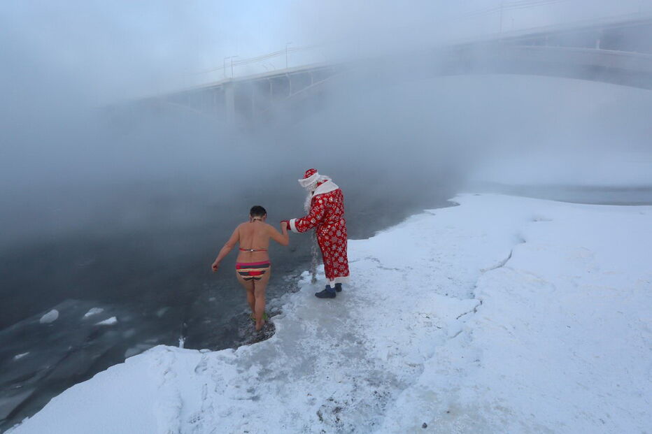 Membros do clube de natação de inverno caminham ao longo de uma escadaria na margem do rio Yenisei, na Rússia, com 26 graus negativos 