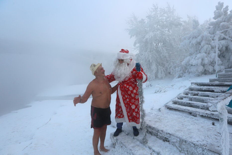 Membros do clube de natação de inverno caminham ao longo de uma escadaria na margem do rio Yenisei, na Rússia, com 26 graus negativos 