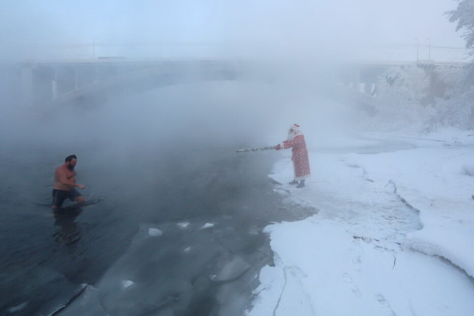 Membros do clube de natação de inverno caminham ao longo de uma escadaria na margem do rio Yenisei, na Rússia, com 26 graus negativos 
