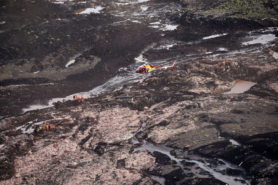 Pessoas e animais entre rios de lama causados pela rutura de barragem no Brasil