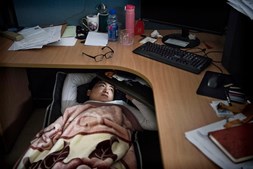 Trabalhador da Huawei descansa debaixo da secretária 