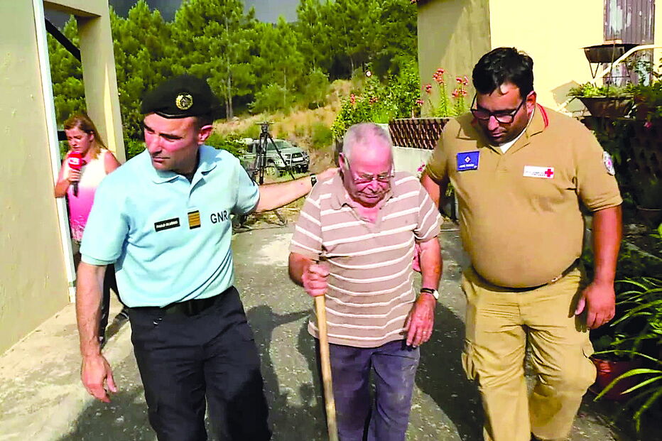 Paulo Silvério, (à esq.) coronel da GNR, comandante distrital de Santarém, a ajudar António Joaquim, que foi retirado de casa  