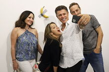 Várias pessoas posam com a obra de arte 'Comediante'