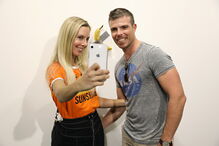 Várias pessoas posam com a obra de arte 'Comediante'