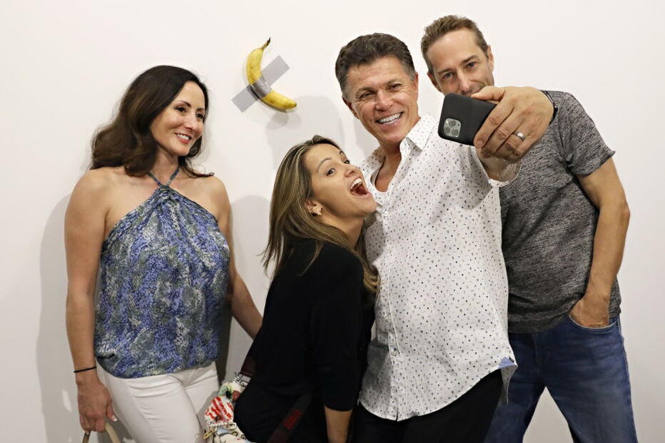 Várias pessoas posam com a obra de arte 'Comediante'