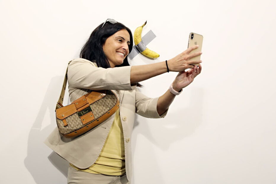 Várias pessoas posam com a obra de arte 'Comediante'