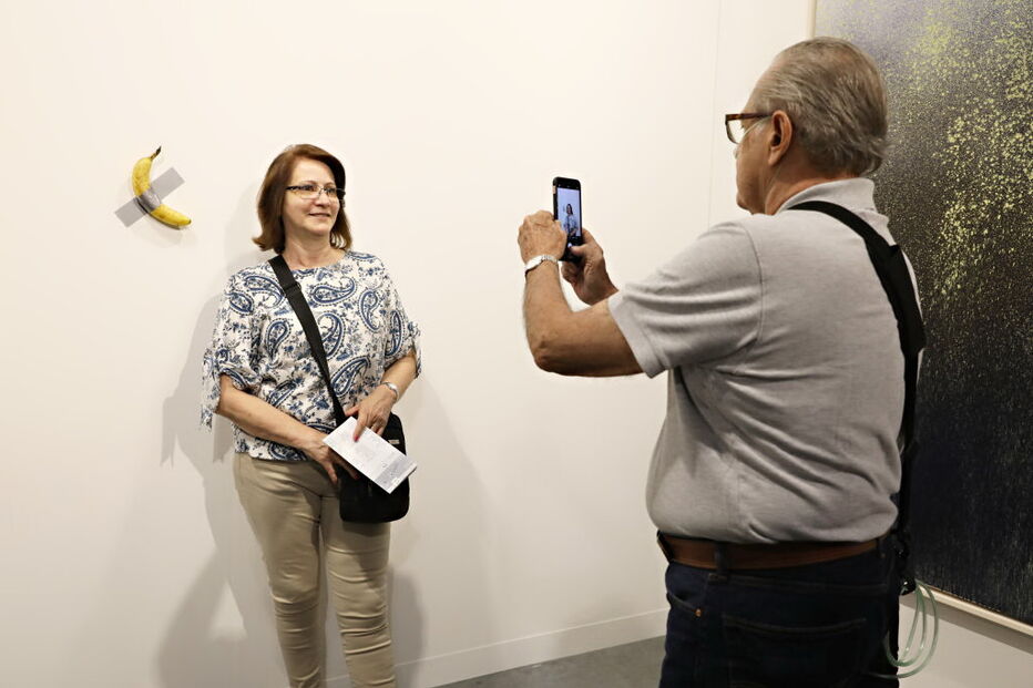 Várias pessoas posam com a obra de arte 'Comediante'