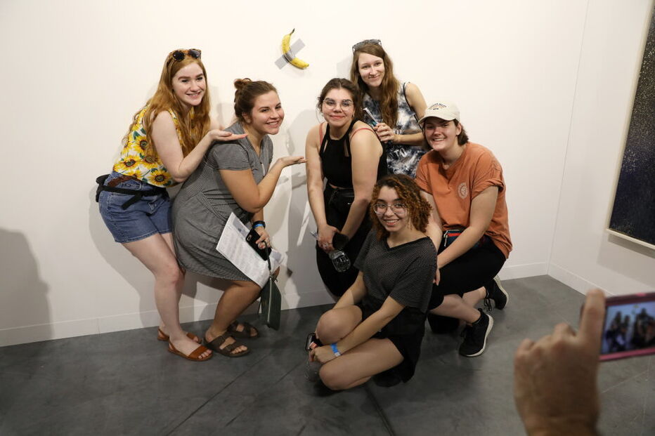 Várias pessoas posam com a obra de arte 'Comediante'