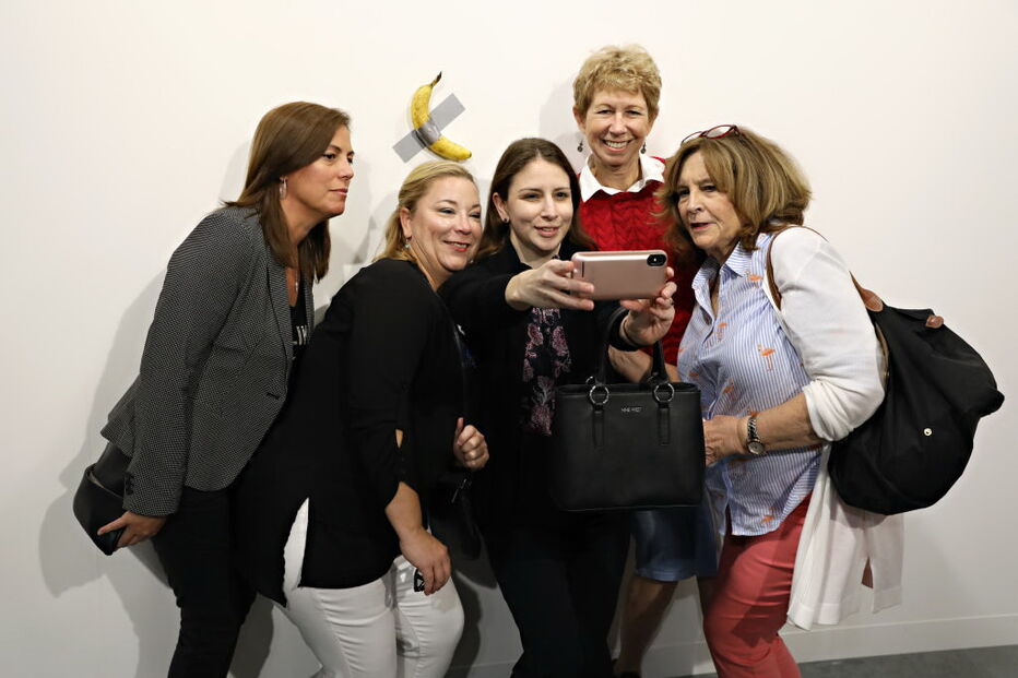 Várias pessoas posam com a obra de arte 'Comediante'