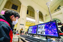 Funcionário na estação ferroviária de Wuhan verifica temperatura das pessoas em monitores 