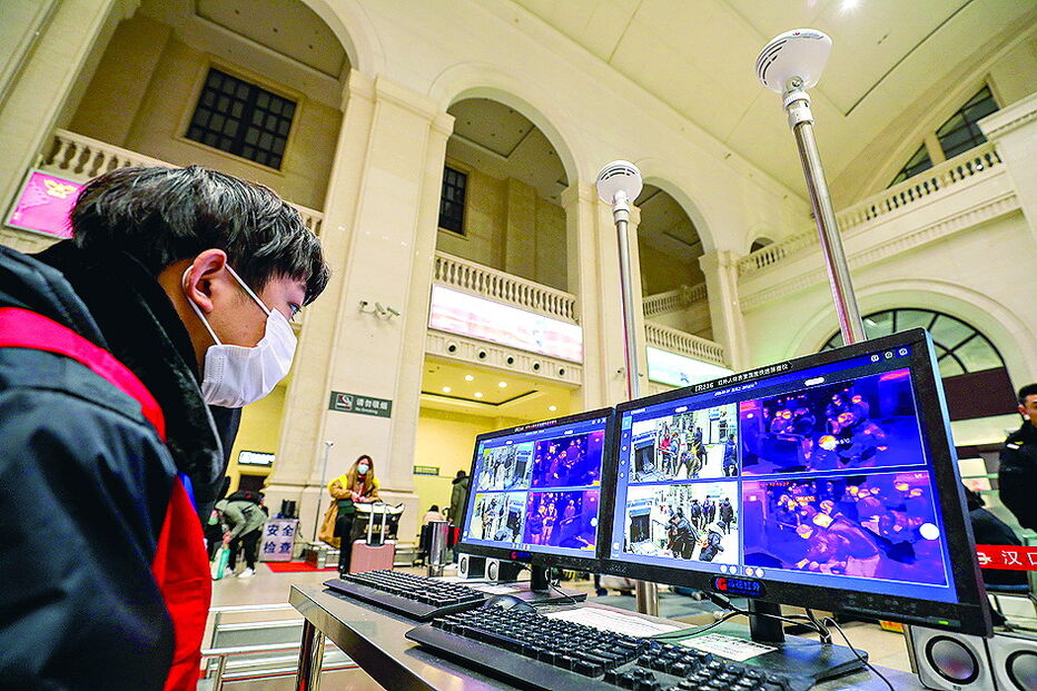 Funcionário na estação ferroviária de Wuhan verifica temperatura das pessoas em monitores 