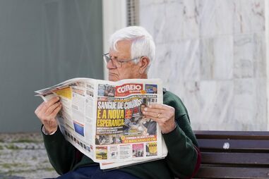 Leitor com o jornal Correio da Manhã, em Lagos
