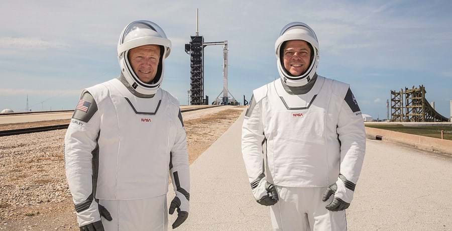 Os astronautas da NASA Doug Hurley (esquerda) e Bob Behkem com o foguetão Falcon 9, da empresa privada SpaceX, ao fundo 